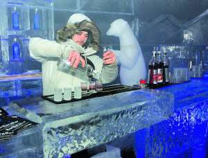Бармен готує коктейлі в льодовому барі в Національному експоцентрі у Києві. Наливає у скляні чарки. Чекає на нову партію крижаного посуду, в якому зазвичай подають напої