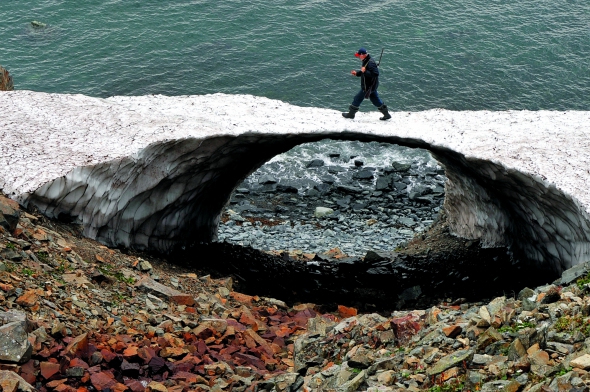Чоловік іде по льодовому мосту на березі Охотського моря. Колима, вересень 2010 року