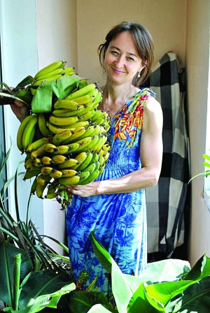 Анна Маркуш тримає банани сорту Київський карлик, вирощені у власній теплиці. Гілка важить до 15 кілограмів