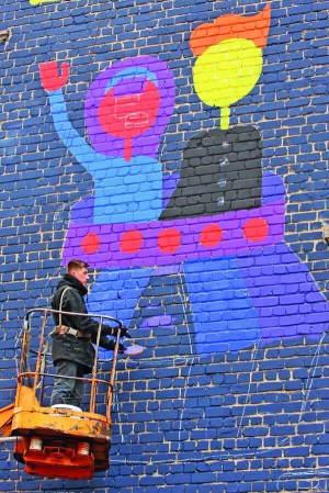 Артем Прут розмальовує стіну багатоповерхівки на вулиці Анрі Барбюса, 11/2, у Печерському районі столиці. До роботи залучили дітей-церебральників