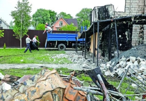 Рятувальники вантажать до машини тіла ­загиблих у пожежі. Щоб опізнати людей, проводитимуть ДНК-експертизи