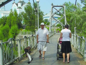 Жителі міста Горішні Плавні — колишнього Комсомольська на Полтавщині, гуляють неподалік Свято-Миколаївського собору. До нього через паркове озеро веде підвісний міст