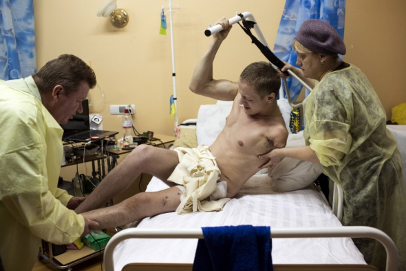 Руслан Карпець - батько двох дітей, з Кременця Тернопільської  області. На фото, зробленому у Київському військовому госпіталі, мама допомагає йому сісти. 