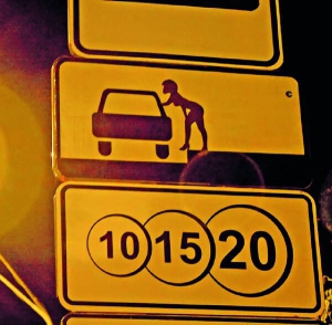 До контуру машини на автомобільному знаку ”Спосіб поставлення транспортного засобу на стоянку” вуличний митець Єжи Коноп’є домалював дівчину. Нижче висить знак ”Платні послуги”