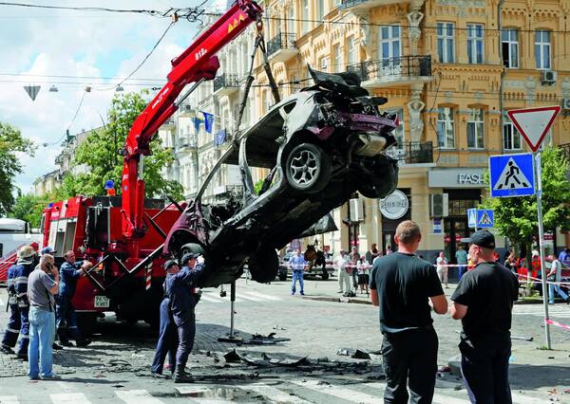 Кран підіймає понівечене авто, за кермом якого сидів Павло Шеремет. Вибух був такої сили, що в сусідніх магазинах зник струм. Журналіст кілька разів крикнув: ”Помогите!”, — кажуть свідки