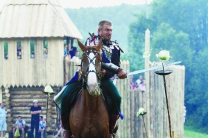Учасник фестивалю ”Ту Стань!” в обладунках давньоруського лицаря вправляється на капусті володіти мечем