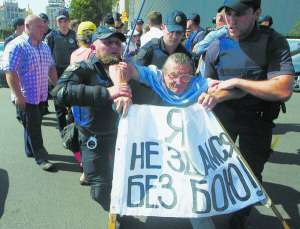 9 серпня поліцейські відтягують учасника мітингу вкладників банку ”Михайлівський” із дороги на Хре­щатику. Близько сотні людей вимагають повернути їхні заощадження