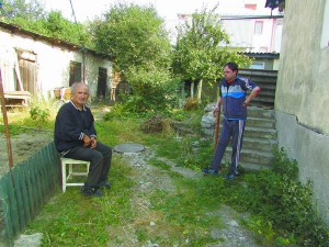 Тарас Войчишин (ліворуч) та Андрій Самофалов розмовляють на подвір’ї свого будинку в Чорткові на Тернопільщині. Раніше Андрій тут мешкав із батьками. Вони померли