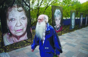 Чоловік проходить повз виставку портретів євреїв, які вижили в концтаборах і гетто під час Другої світової війни. Світлини встановили в меморіальному заповіднику ”Бабин Яр”