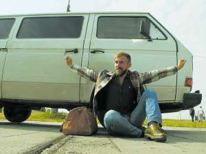 Леонід Єзерський сидить на асфальті під час виставки ретро-автомобілів у столиці. 7 жовтня вирушив у навколосвітню подорож автостопом