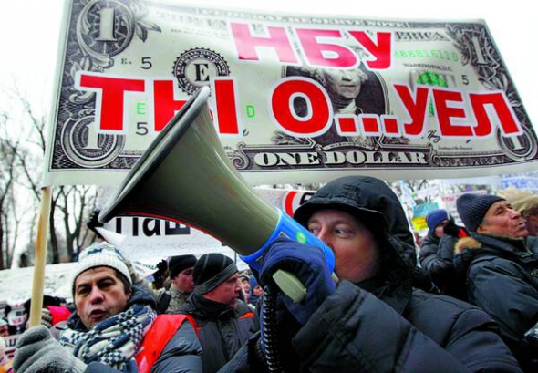 Учасники мітингу під приміщенням Національного банку України 16 грудня позаторік обурені політикою регулятора. Протягом року гривня знецінилася удвічі – з восьми гривень за долар офіційний курс упав до майже 16