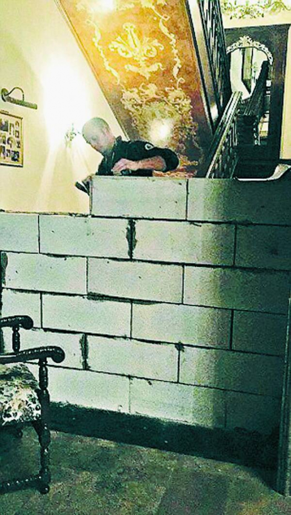 Робітник укладає бетонну стіну у триповерховому маєтку подружжя Цвітненків. Так за рішенням суду поділили спільну нерухомість пари