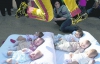 Матери кладут детей на коврики на тротуарах