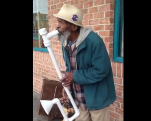 Уличный музыкант играет джаз на водосточной трубе