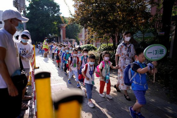 Учащиеся в защитных масках выходят из начальной школы в Ухане, провинция Хубэй.