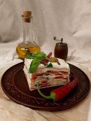 Торт із лаваша прикрашають перцем чилі, оливками та базиліком