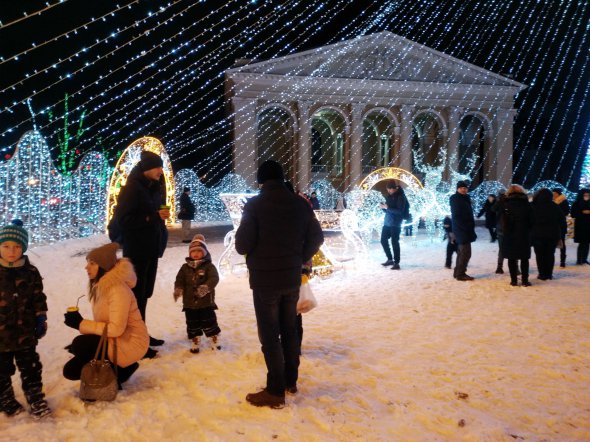Горожане гуляют с детьми под световым куполом центральной елки на Театральной площади