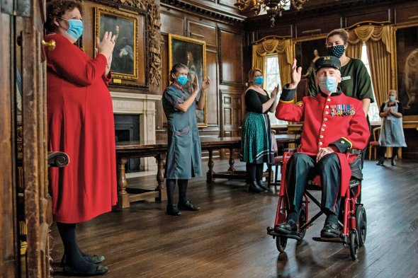 Працівники госпіталю в Челсі вітають 98-річного Роберта Джеймса Саллівана після вакцинування від коронавірусу 23 грудня 2020-го. У закладі живуть британські ветерани. Будинок для самотніх колишніх військових заснував король Чарльз II 1682 року