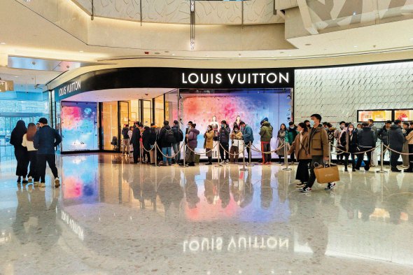 Люди вишикувалися в черзі до бутика Louis Vuitton у торговому центрі Шанхая, Китай, 31 грудня торік. У листопаді там запровадили посилений карантин після спалаху коронавірусу. За три тижні обмеження послабили. Торговим центрам дозволили працювати