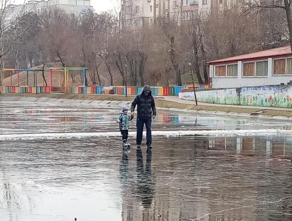 На хрупком льду мужчина учил ребенка кататься на коньках