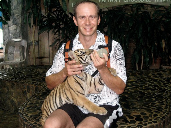 Сергій Пилипчук годує з пляшечки тигреня в зоопарку в Таїланді. Подорожував країною 2005 року