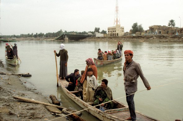Чоловіки на човнах перевозять людей через річку Євфрат у місті Самава в Іраку 23 лютого 1991-го. Міст зруйнував американський бомбардувальник під час операції ”Буря в пустелі”. Про її початок оголосили в Білому домі 16 січня. Мали звільнити Кувейт від іракської окупації. Участь взяли 32 держави. Задіяли 700 тисяч солдатів. Іракські війська зазнали поразки