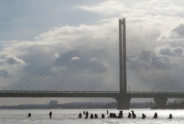 Количество рыбаков на Днепре в Киеве увеличилось, когда реку покрыло крепким льдом. Одно из популярных мест в столице - возле парка Наталка у Северного моста на Оболони