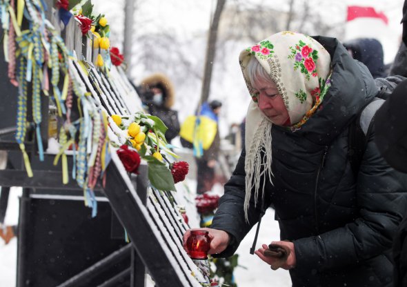 Женщина ставит лампадку у мемориала Героям Небесной сотни, установленный на месте расстрелов в феврале 2014