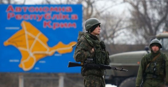 Російський військовий стоїть напроти дорожнього знаку в Криму. Весна 2014-й рік