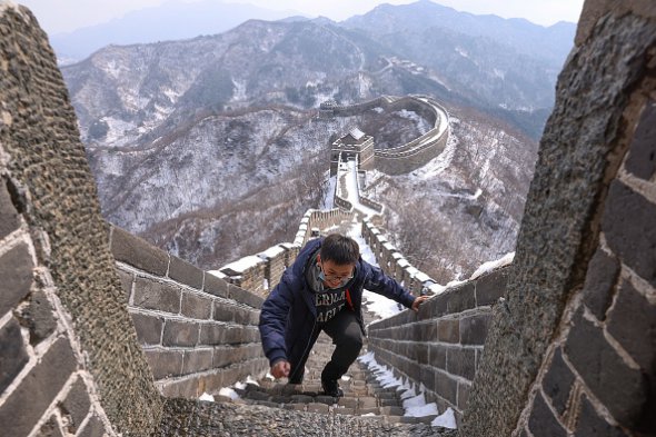 Турист идет заснеженной лестницей Великой китайской стены 23 февраля 2021-го. Обычно многолюдный памятник архитектуры, сейчас - полупустой. Из-за пандемии коронавируса поток туристов за год сократился на 60%