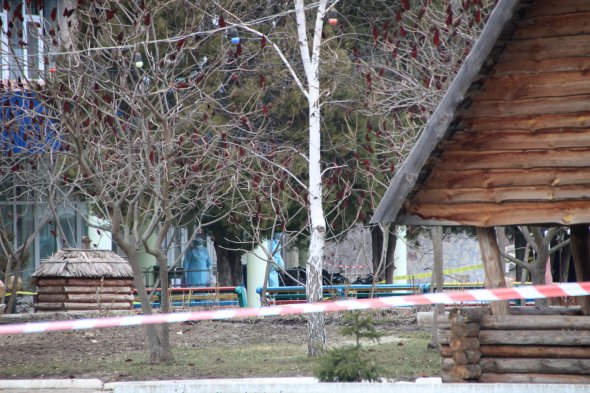 Люди, одягнені в костюми спецзахисту, обробляють деззасобами речі біля входу до корпусу медцентру "Нові Санжари", де проходить обсервація евакуйованих з КНР