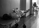 "Найкраща медицина - в СРСР".  Жінка після пологів лежить на каталці в коридорі відділення зі стаканом "цілющого кефіру" в руках. 1981 рік.
