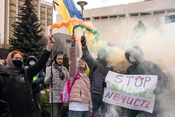 Протестующие держат дымовые шашки во время митинга возле здания, в котором проходит съезд судей Украины в Киеве, 9 марта.