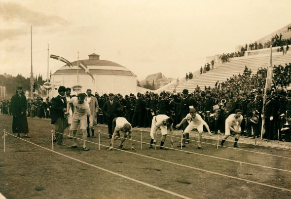 Спортсмени готуються бігти дистанцію 100 метрів на стадіоні ”Панатінаїкос” в Афінах, квітень 1896 року. Забіг відбувся в рамках І Олімпійських ігор. Проходили змагання у 12 дисциплінах. Переможцями в командному заліку стали Сполучені Штати Америки – 11 золотих медалей. За ними – Греція з десятьма перемогами та Німеччина, що дев’ять разів посідала перші місця