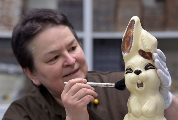 Руководитель шоколадной фабрики "Гиммельфортер" Сильке Виенольд удаляет мягкой щеткой лишние части из шоколадного зайца