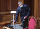 Работник проводит дезинфекцию в зале заседаний во время очередного заседания Верховной Рады Украины