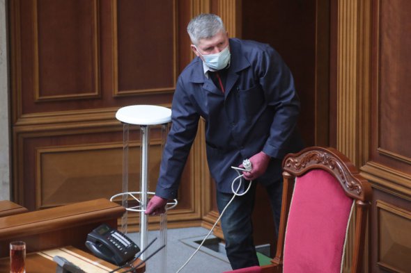 Работник проводит дезинфекцию в зале заседаний во время очередного заседания Верховной Рады Украины