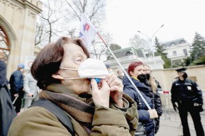 Жінка піднімає захисну маску і свистить під час акції протесту біля російського посольства в Празі 18 квітня. Чехів обурила причетність російських спецслужб до вибуху на складі боєприпасів 2014 року. Активісти облили будівлю кетчупом. Він символізує кров на руках Кремля