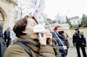 Жінка піднімає захисну маску і свистить під час акції протесту біля російського посольства в Празі 18 квітня. Чехів обурила причетність російських спецслужб до вибуху на складі боєприпасів 2014 року. Активісти облили будівлю кетчупом. Він символізує кров на руках Кремля