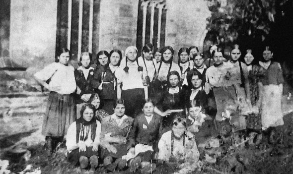 Параска Провоторова (четверта ліворуч) з бранками німецького трудового табору стоїть біля костелу в Ганновері. Поряд розташована фабрика запчастин до літаків, на якій вони працювали. 1943 рік