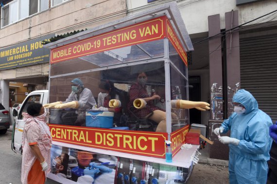 Врачи тестируют людей на коронавирус в мобильном пункте на улицах Нью-Дели