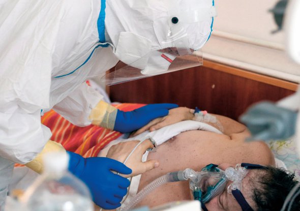 Професор Сергій Дубров у ковідному відділенні столичної лікарні оглядає пацієнта, підключеного до апарата штучної вентиляції легень. Знімок зроблений 26 січня цього року. За час пандемії на коронавірус захворіли понад два мільйони українців. Померли більш як 45 тисяч
