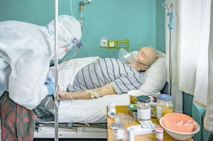 Лікар перевіряє стан хворого на коронавірус чоловіка, який лежить із кисневою маскою в палаті інтенсивної терапії київської лікарні. В Україні спостерігається спад захворюваності на ковід. Щодня в середньому фіксують до 3500 інфікованих