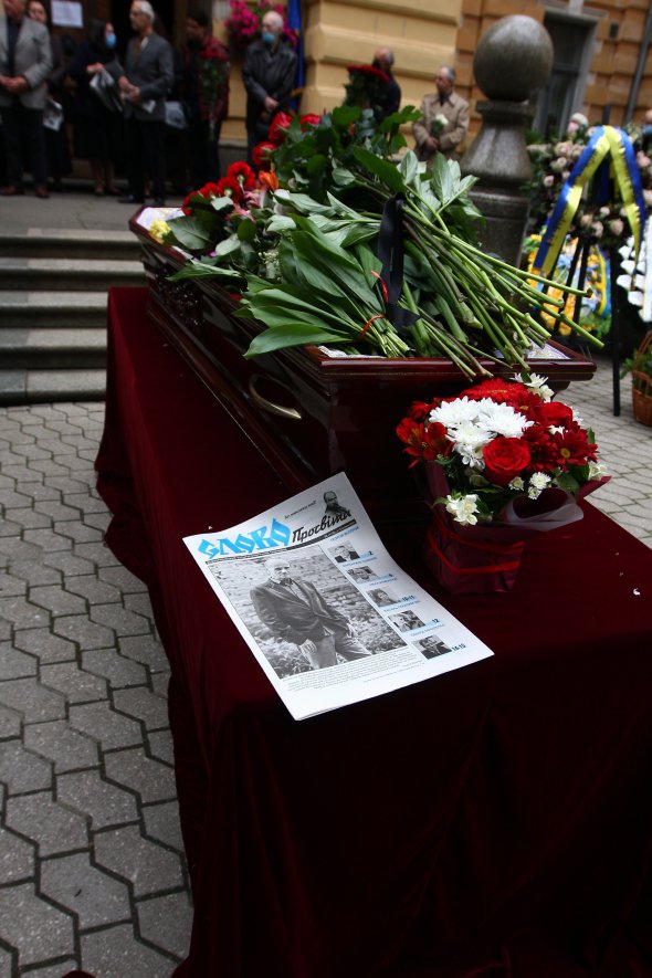 Журналистка из издания "Слово Просвіти" подходит к гробу и кладет рядом газету