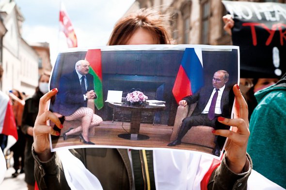 Учасниця маршу солідарності з Білоруссю в польському Кракові тримає плакат, який висміює залежність самопроголошеного президента Олександра Лукашенка від російського диктатора Володимира Путіна, 29 травня 2021 року