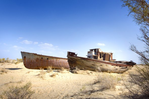 Два судна стоят в песке неподалеку Муйнака - когда-то рыбацкого городка в Узбекистане. Воды Аральского моря отступали столь стремительно, что корабли не успевали забирать