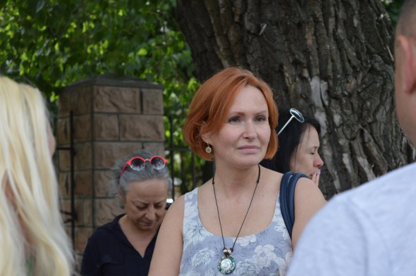 Юлія Кузьменко очікує на повернення до судової зали. На її нозі чорний браслет