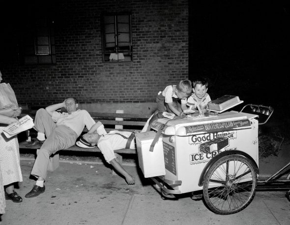 Діти дістають морозиво з візка в Нью-Йорку 13 липня 1954-го. Вуличний продавець стомився від спеки й заснув. Того дня в місті зафіксували найвищу річну температуру +37°C. У парках роздавали холодну воду й дозволили купатись у фонтанах.