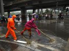 Рабочие очищают затопленную улицу после проливного дождя в утренний час пик в центральном деловом районе Пекина