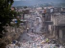 Люди переходят заваленный мусором ручей рядом с домами через неделю после убийства президента Жовенеля Мойза в Порт-о-Пренсе, Гаити